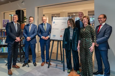 Alt tekst: 6 ondertekenaars + Gerard Hendriks bij bord met handtekeningen